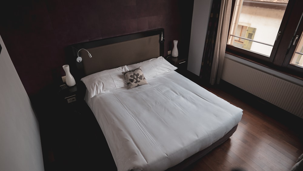 a white bed sitting in a bedroom next to a window