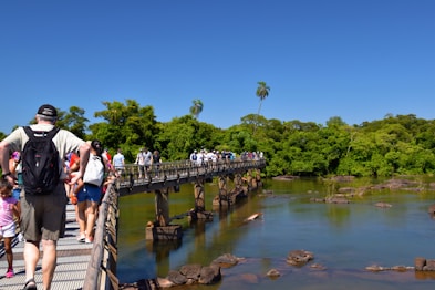 a group of people walking across a bridge over a river