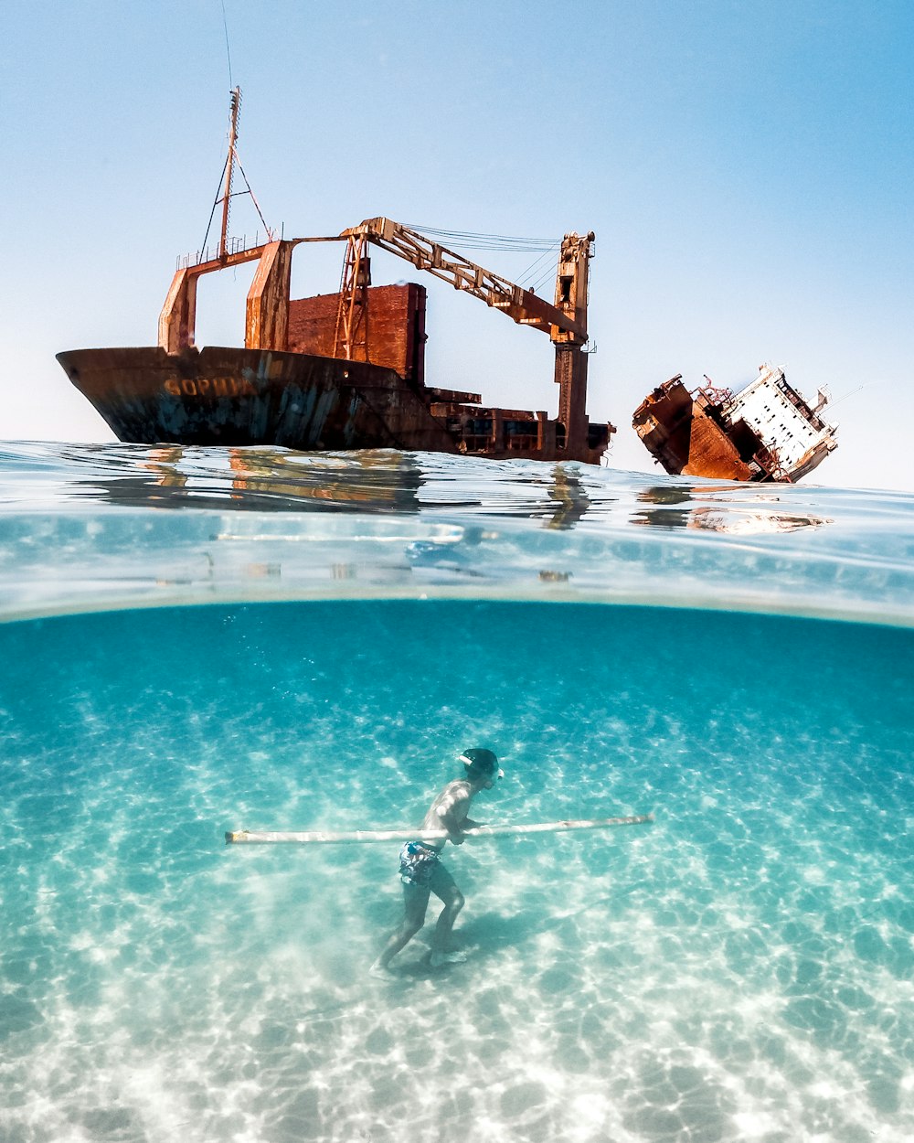 a person in a body of water with a boat in the background