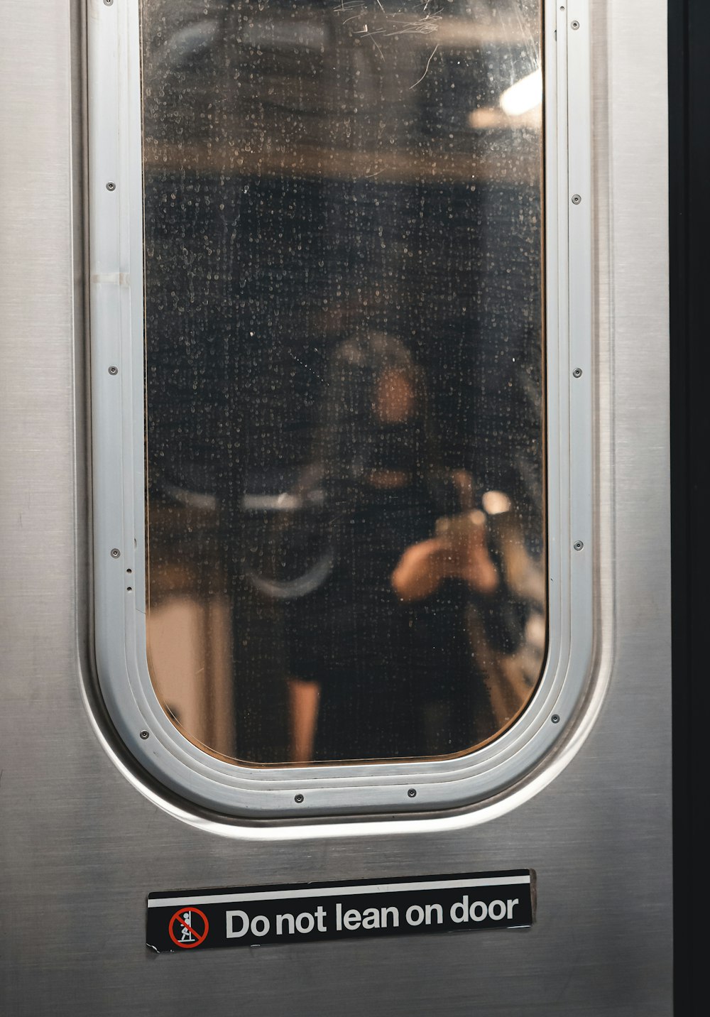 a woman taking a picture of herself through the window of a train