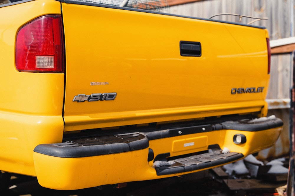 the rear end of a yellow pickup truck