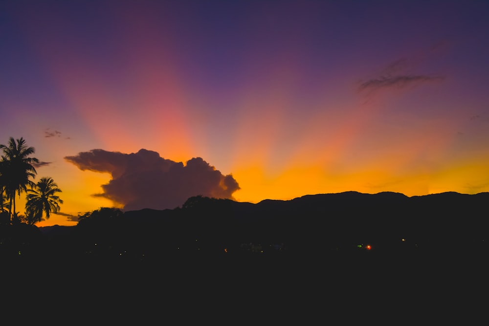 the sun is setting over the mountains and palm trees