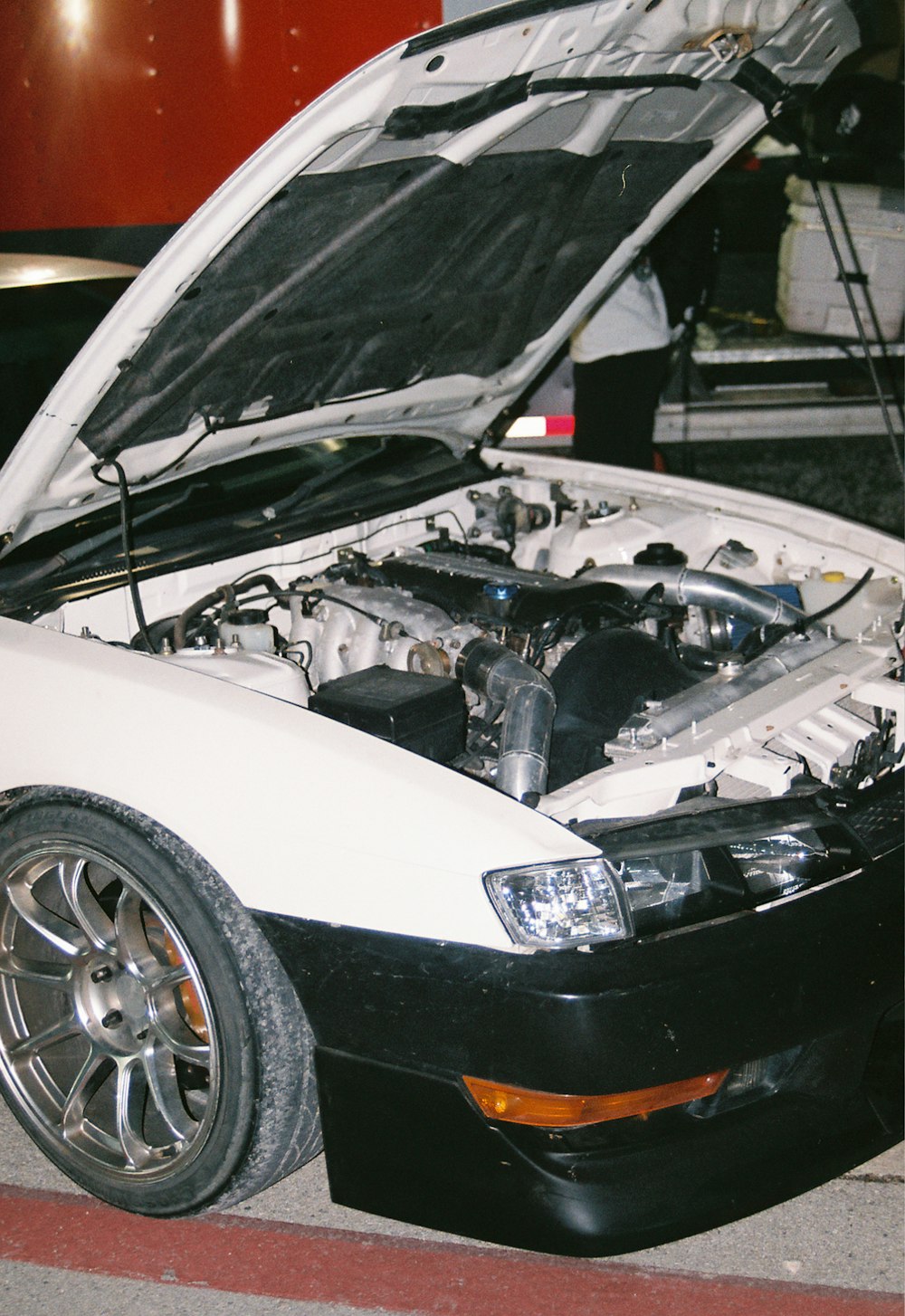 a white car with its hood open on the street