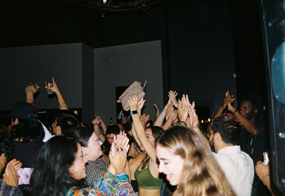 a group of people standing around each other with their hands in the air