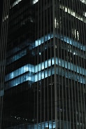 Close-up of a modern apartment building facade with metallic silver accents under neon blue lighting.