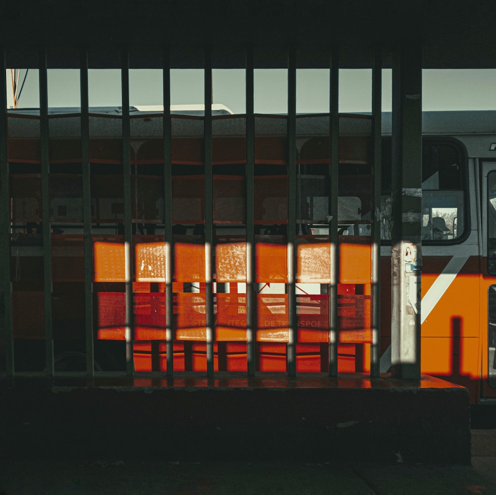 a bus behind a fence with red chairs behind it