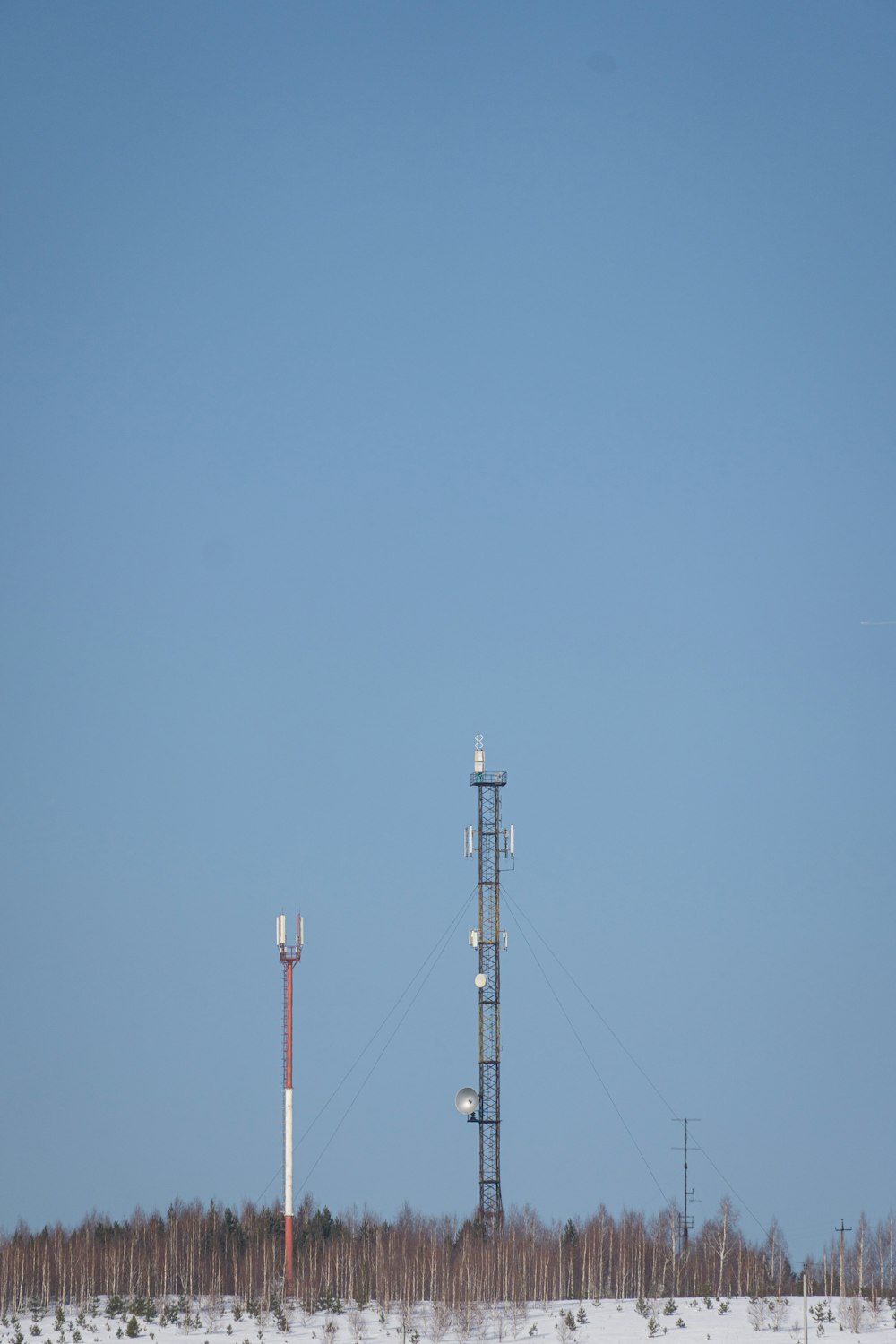 a couple of cell towers sitting in the middle of a snow covered field
