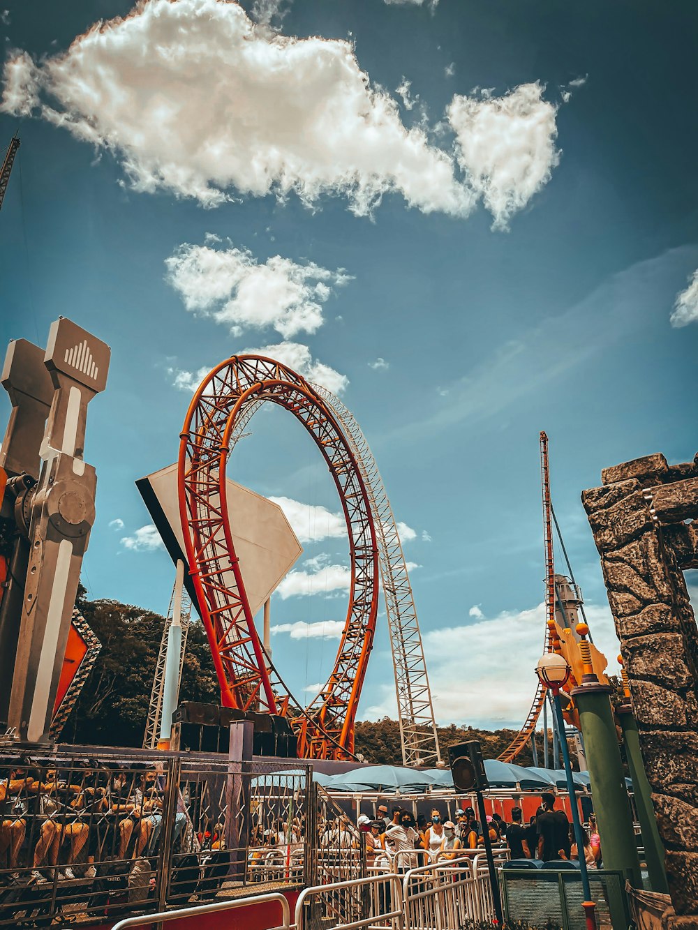 a roller coaster at a theme park under a cloudy blue sky
