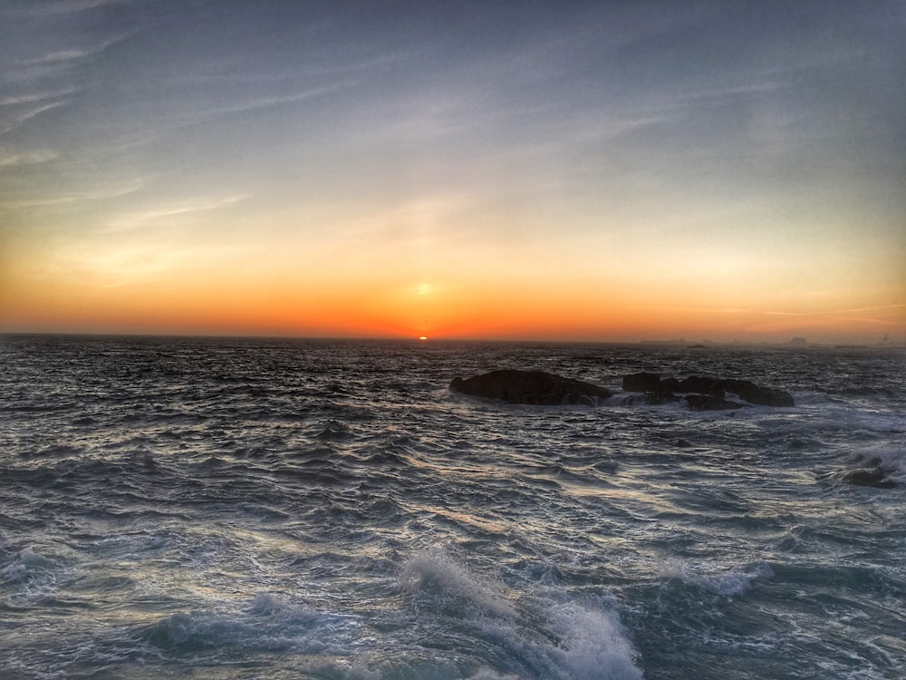 the sun is setting over the ocean with waves