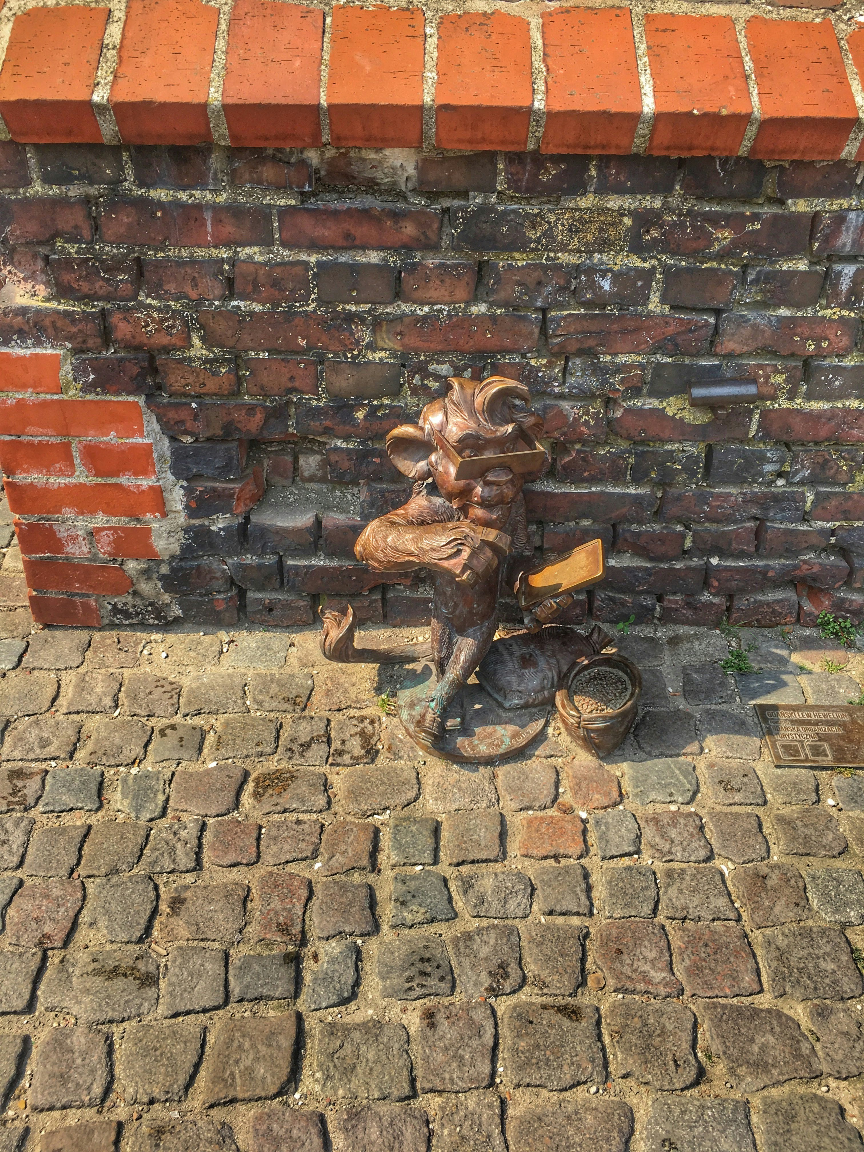 a statue of a person sitting on a chair next to a brick wall