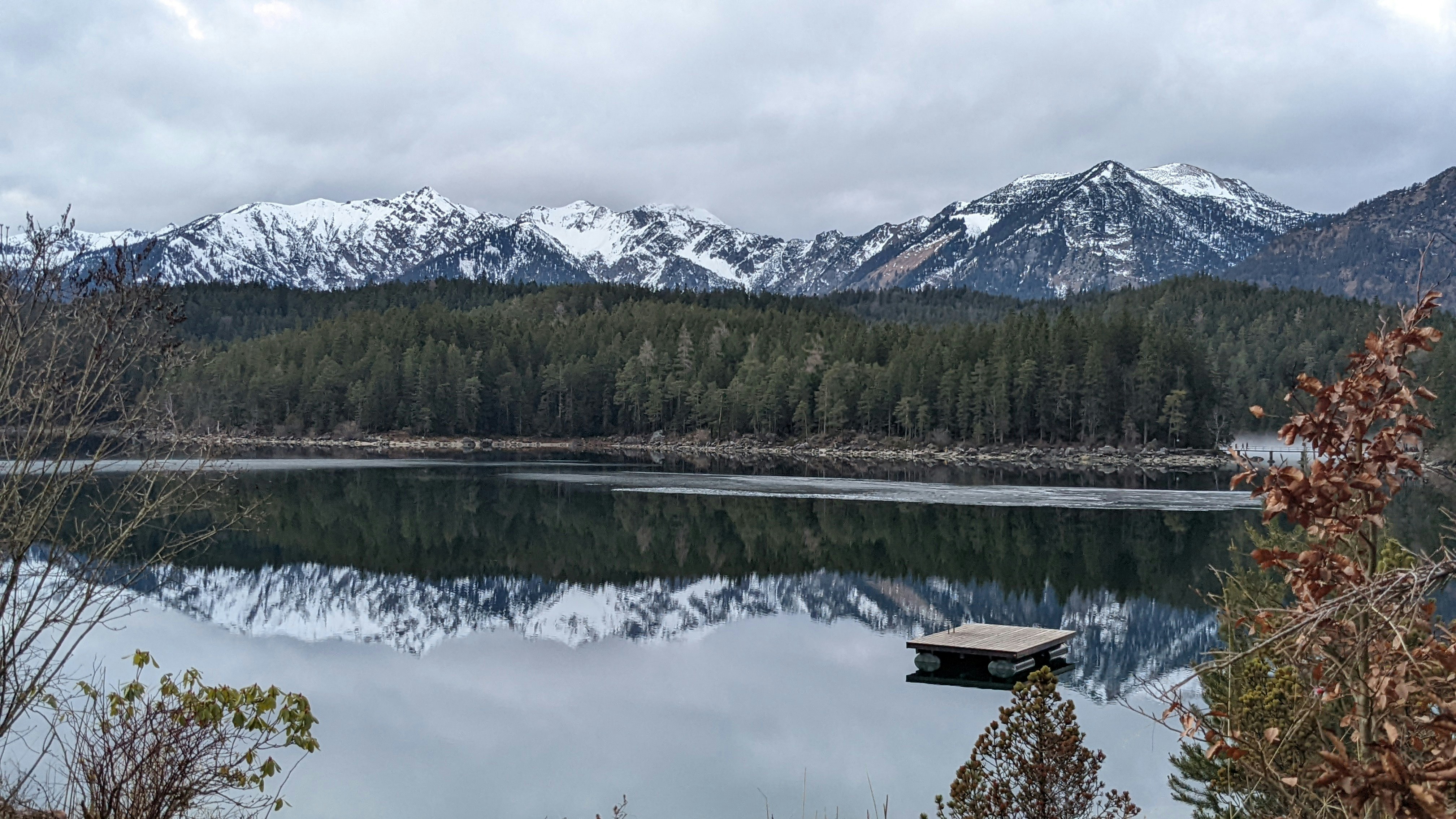 um lago cercado por montanhas com uma doca em primeiro plano