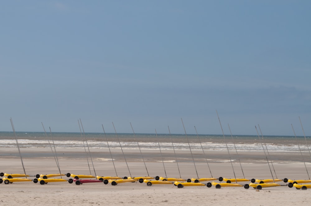 a row of yellow boats sitting on top of a sandy beach