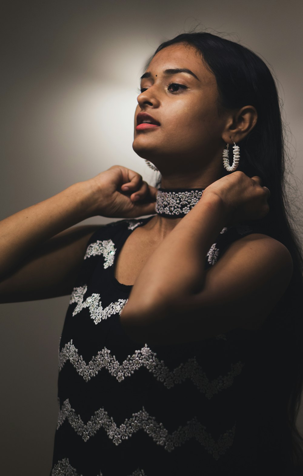 a woman wearing a black and white dress and a pair of earrings