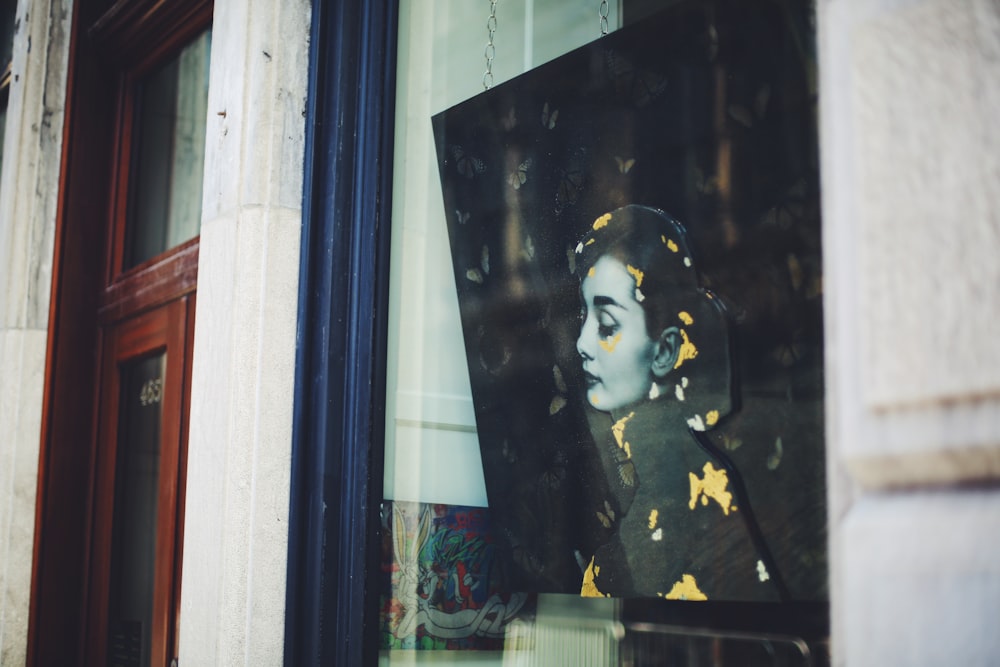 a picture of a woman's face is seen through a window