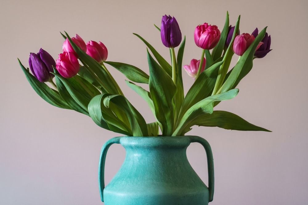 a blue vase filled with pink and purple tulips