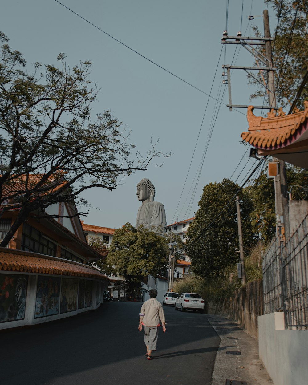 a person walking down a street with a large buddha statue in the background