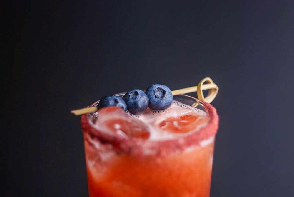 a close up of a drink with blueberries on the rim
