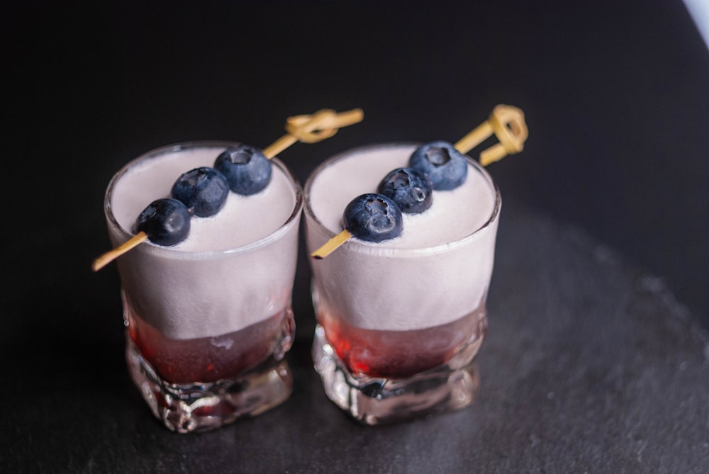 a couple of glasses filled with blueberries on top of a table