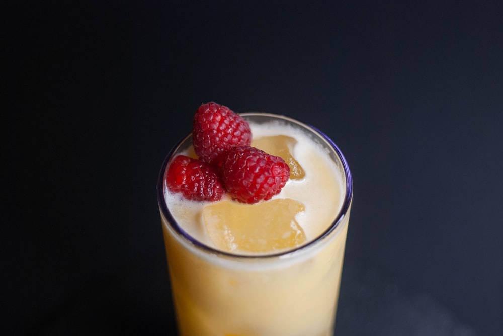 a close up of a drink with raspberries on top