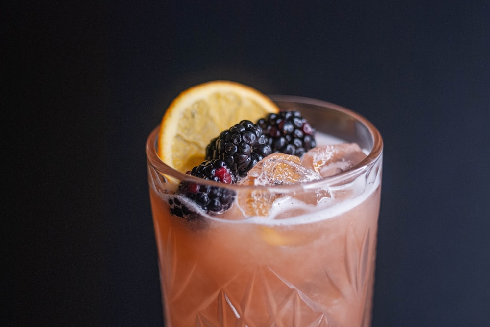 a close up of a drink with fruit on the rim