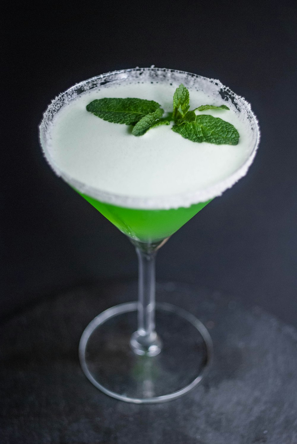 a green and white drink in a martini glass
