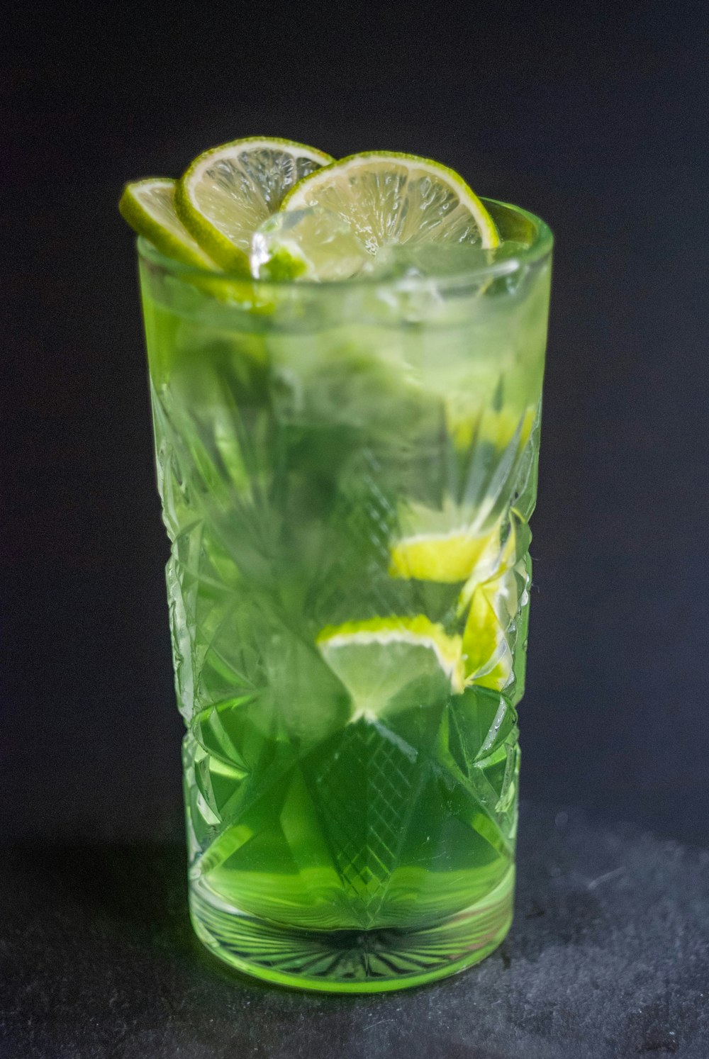 a green drink with limes and mints in a glass