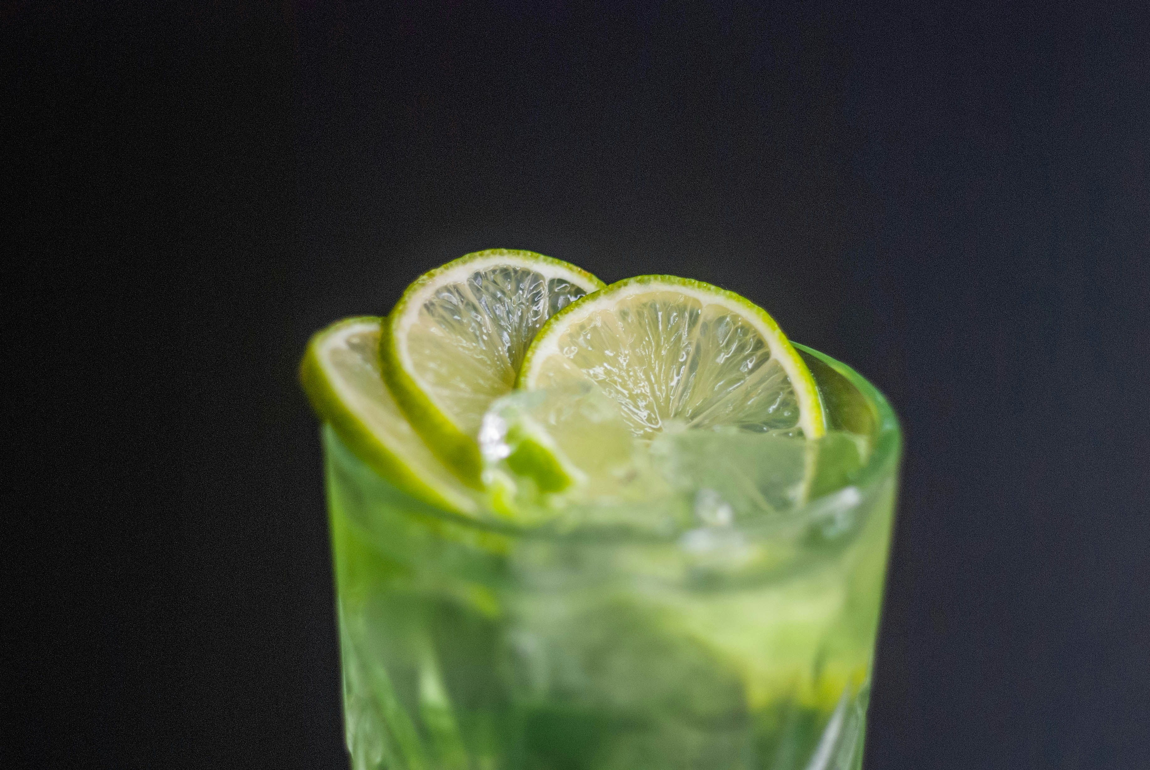 a close up of a drink with limes on the rim