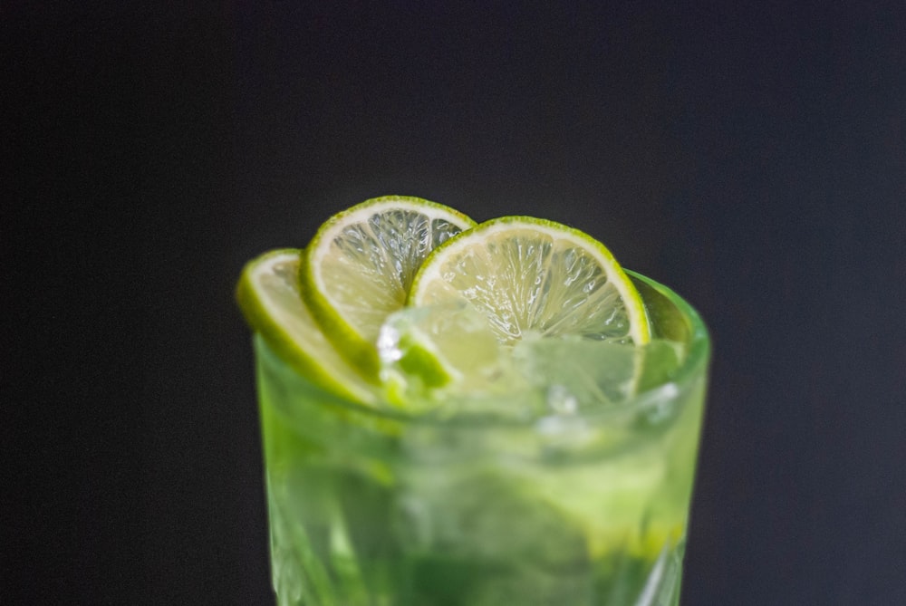 a close up of a drink with limes on the rim
