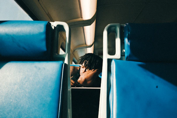 A serene traveler resting comfortably on a train seat, supported by a plush ergonomic neck pillow as golden sunset light filters through the window.