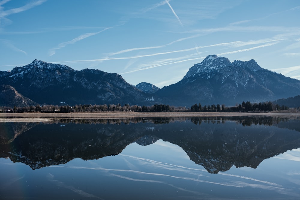 the mountains are reflected in the still water of the lake