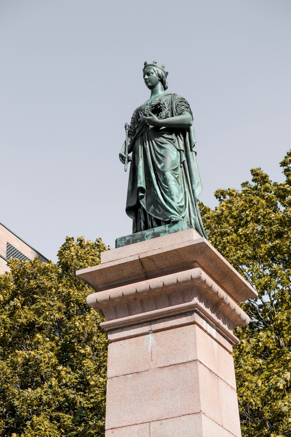 a statue of a woman standing next to a tree