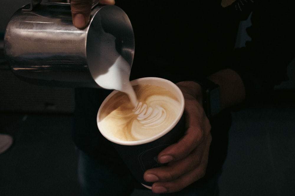 a person pouring a cup of coffee into a cup