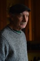 an older man wearing a hat in a kitchen