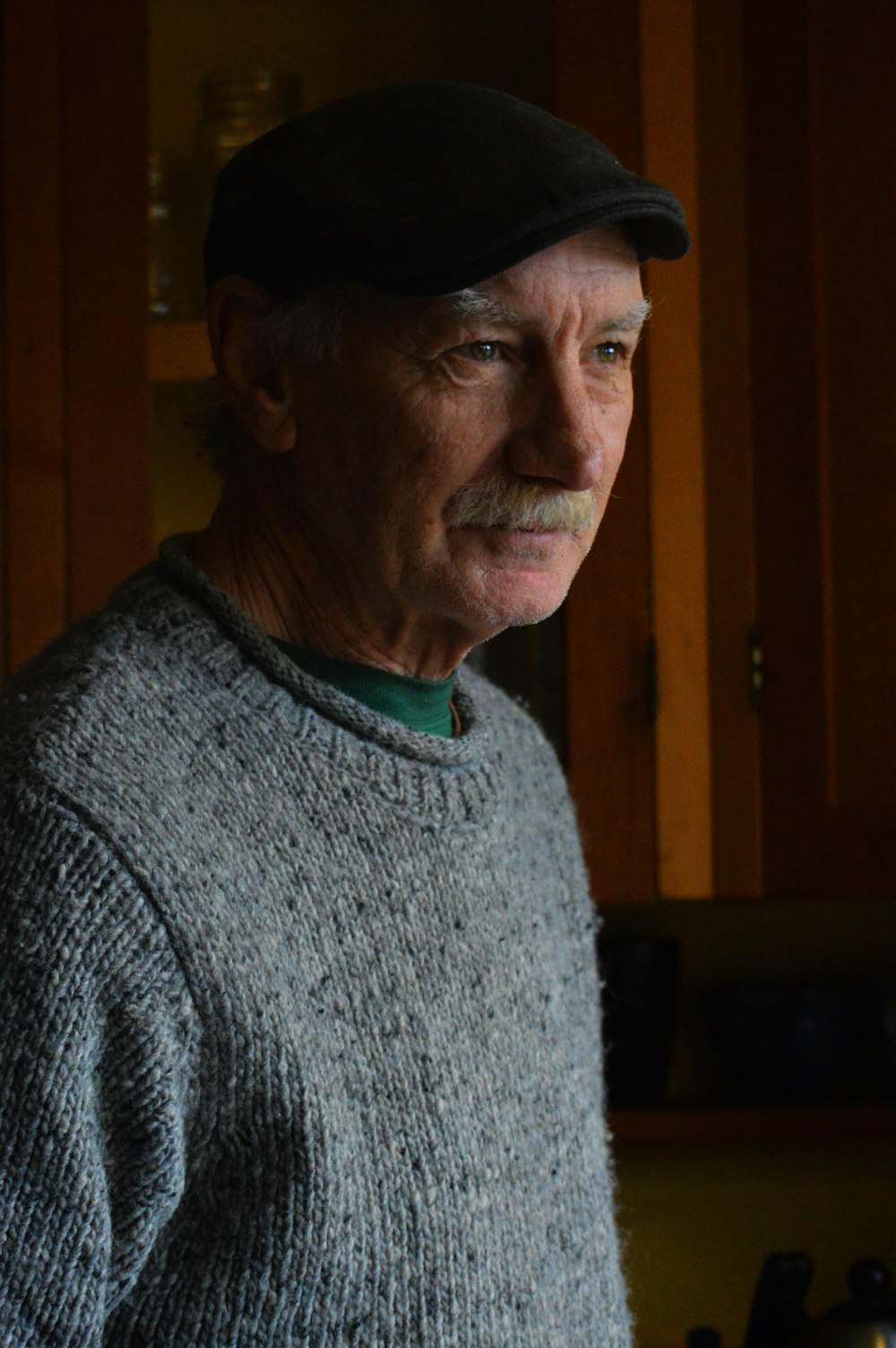 an older man wearing a hat in a kitchen