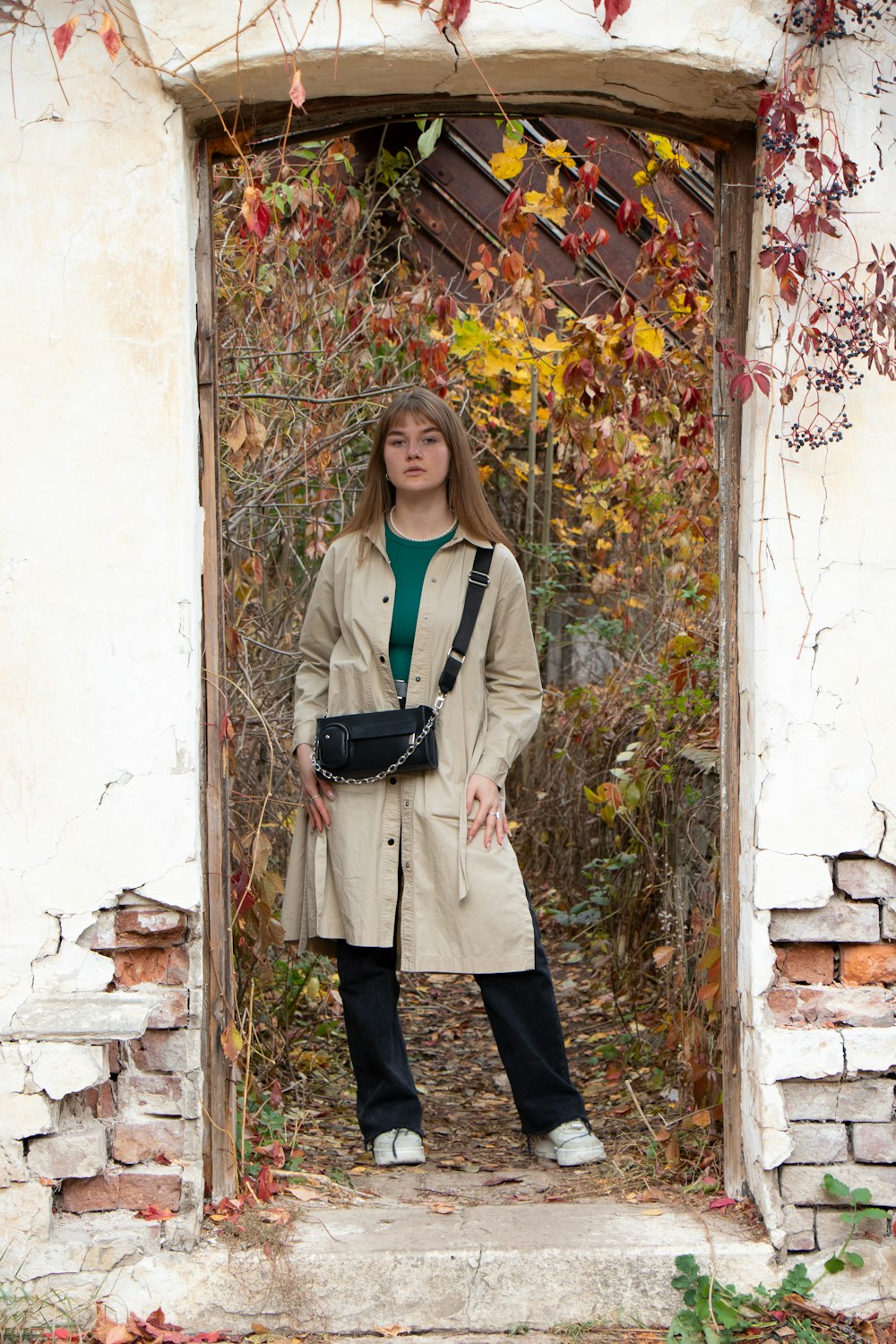 a woman in a trench coat standing in a doorway