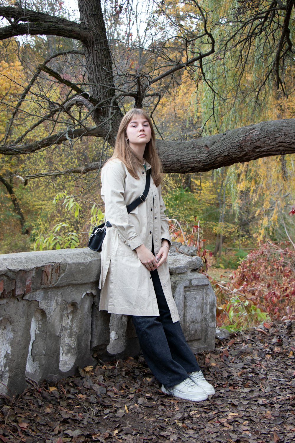 Eine Frau sitzt auf einer Steinmauer neben einem Baum