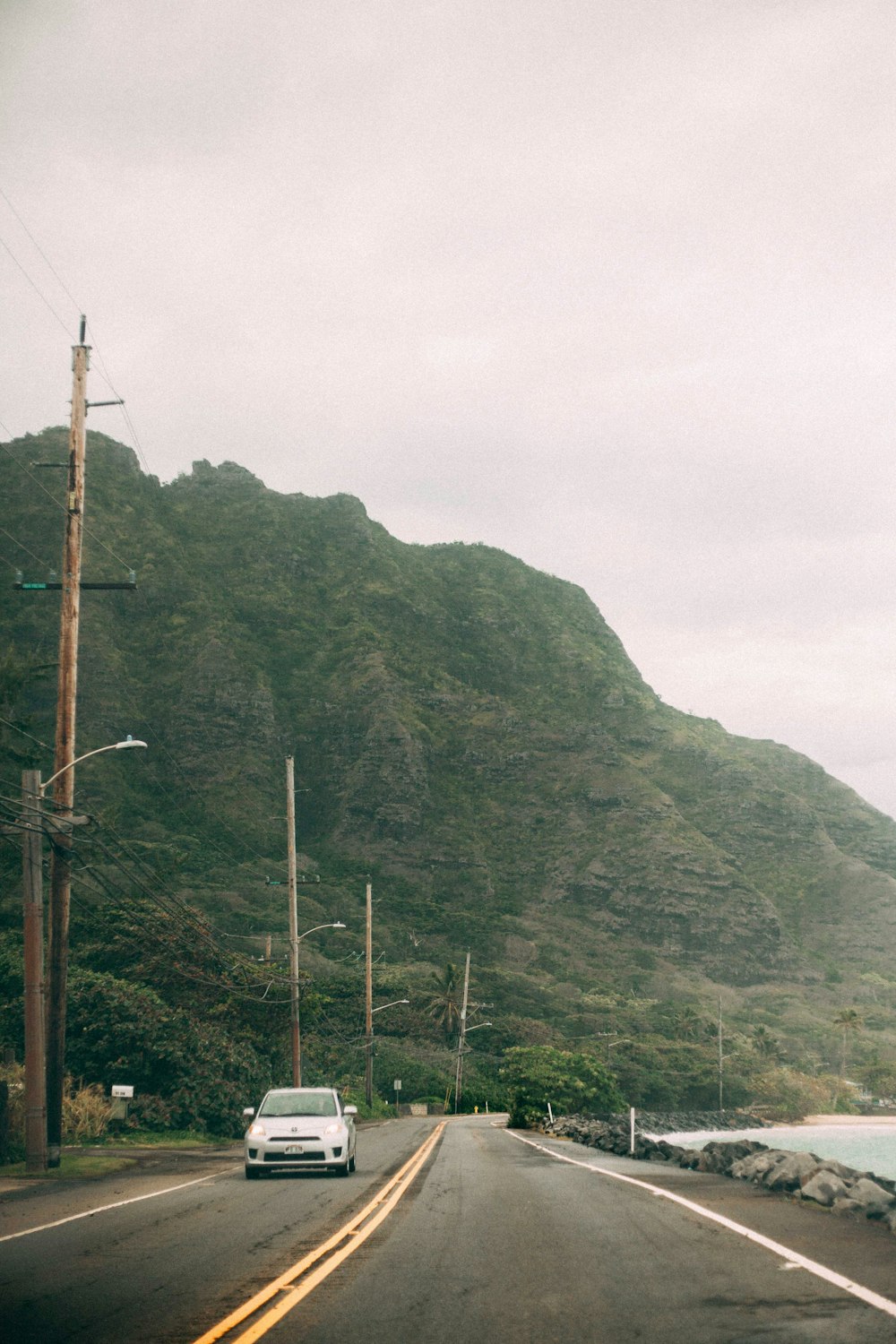 a car driving down a road next to a mountain