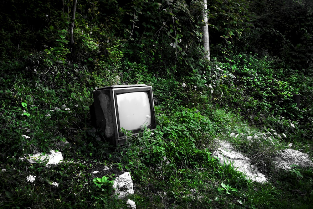 an old tv sitting in the middle of a field