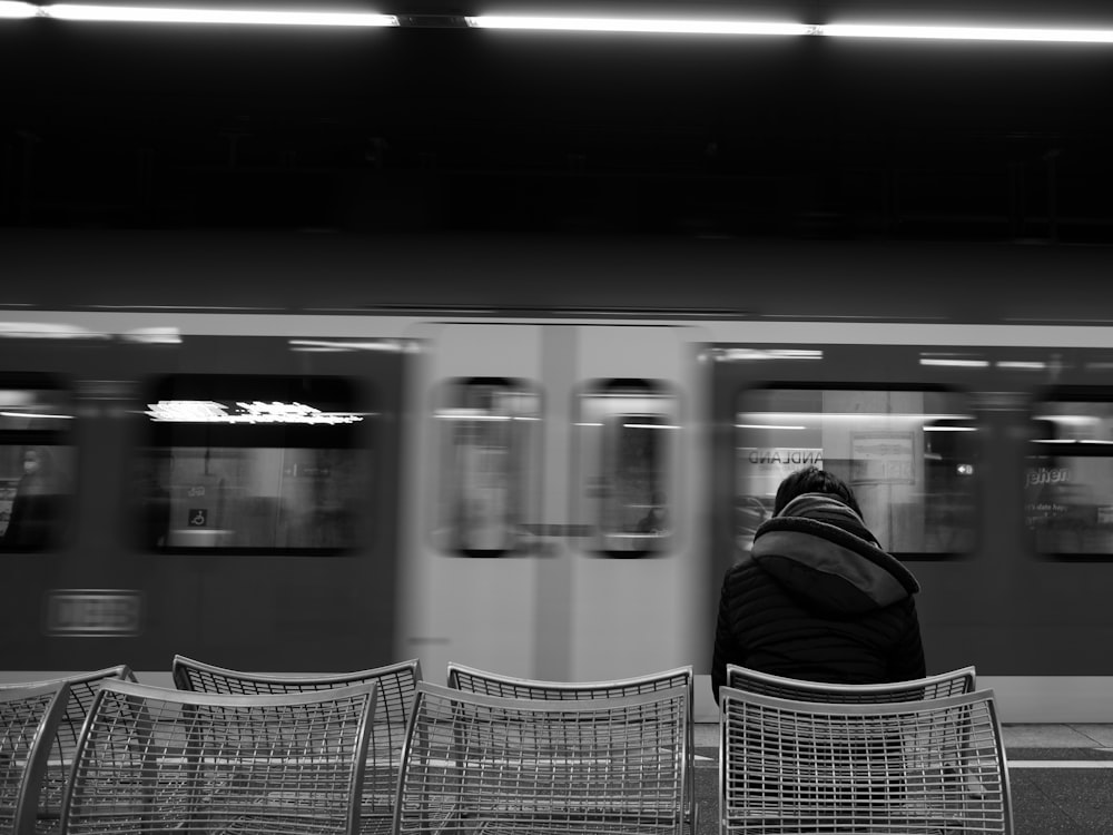 a person sitting on a bench in front of a train