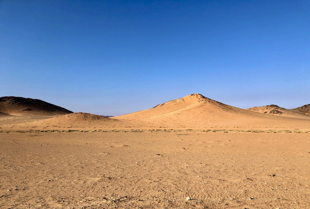 Eine Wüstenlandschaft mit ein paar Hügeln in der Ferne