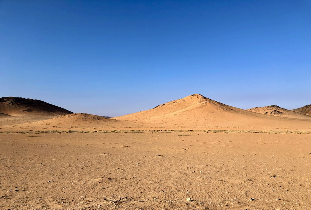 a desert landscape with a few hills in the distance