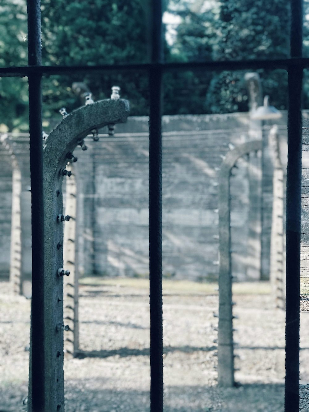 a gated area with a stone wall and trees in the background