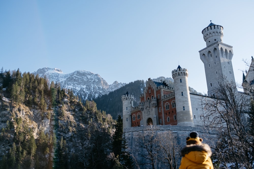 a person in a yellow jacket standing in front of a castle
