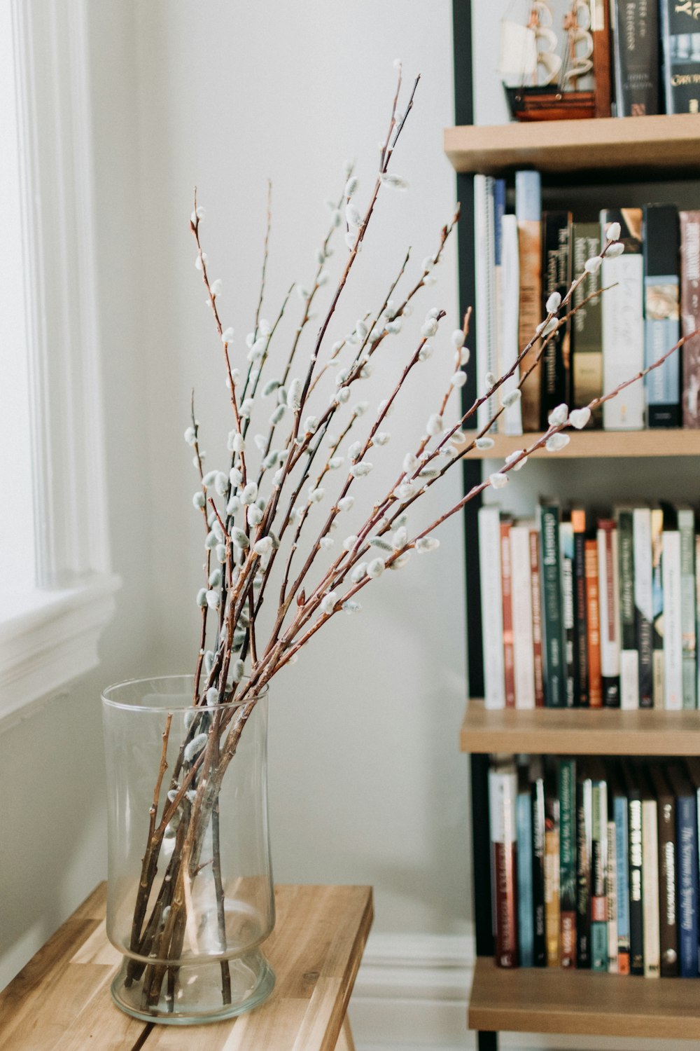 a vase filled with branches on top of a wooden table
