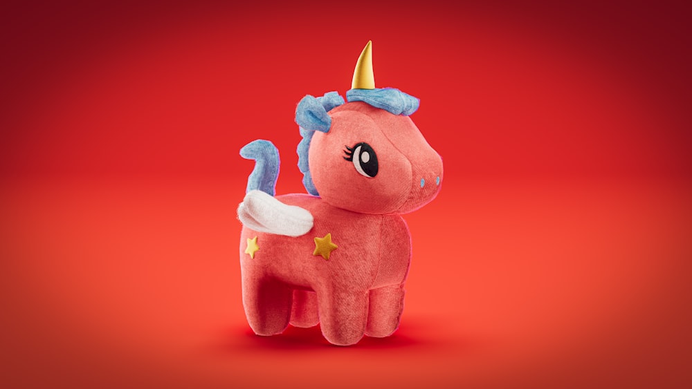 a pink stuffed animal with a gold horn on its head