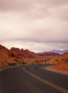 Two riders cruising through a winding desert highway with red rock formations.