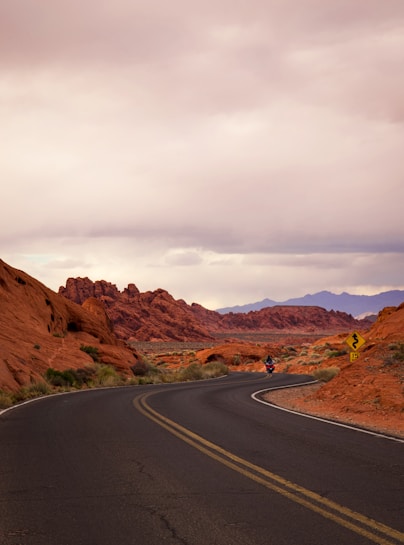Two riders cruising through a winding desert highway with red rock formations.