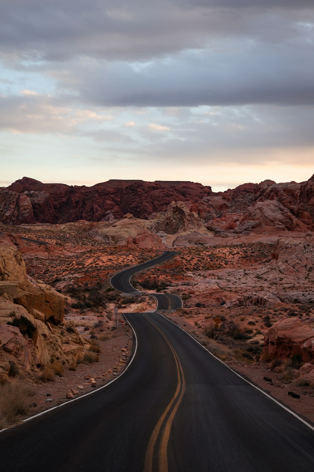 a road in the middle of a desert with mountains in the background