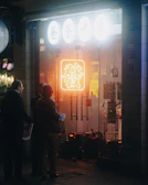 Group of friends laughing in dark streetwear under purple neon signs.