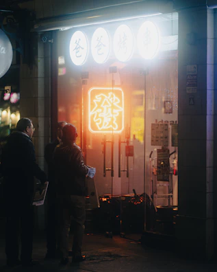 Group of friends laughing in dark streetwear under purple neon signs.